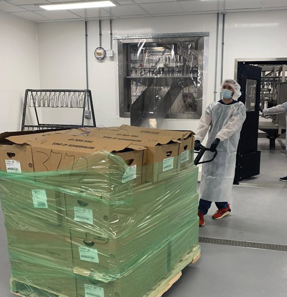student using a pallet jack to pull a pallet full of boxes